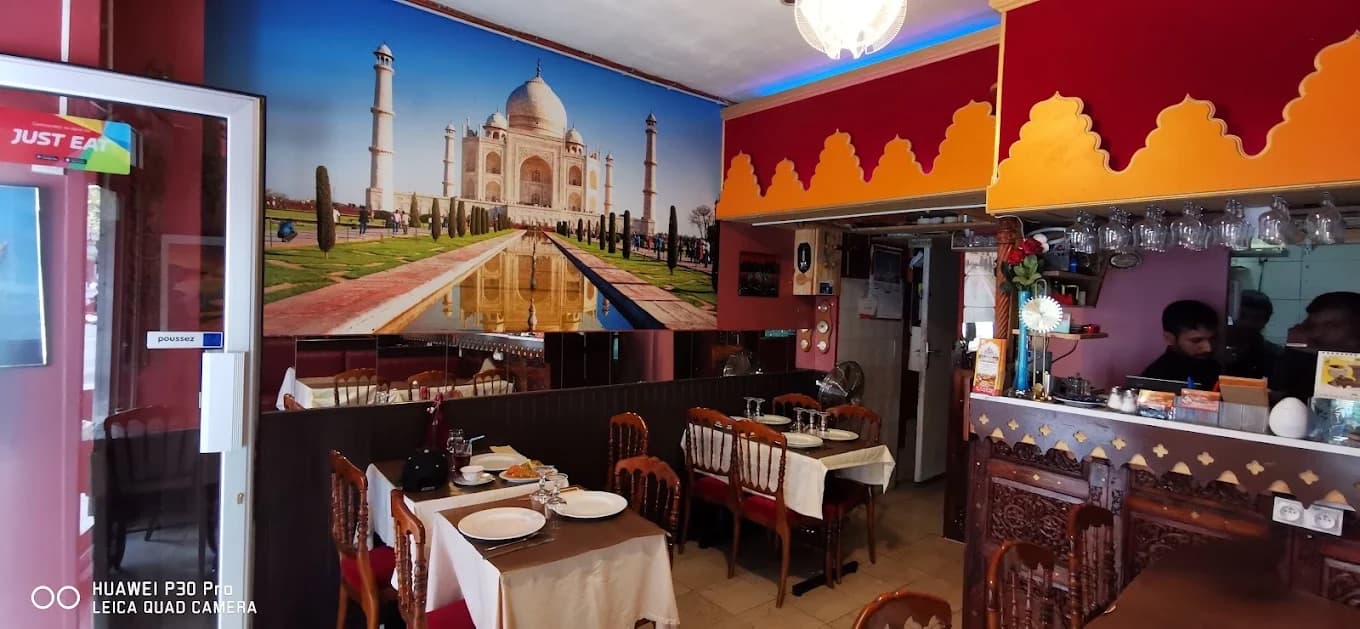 La salle du restaurant, ses tables dressées et sa grande fresque du Taj Mahal