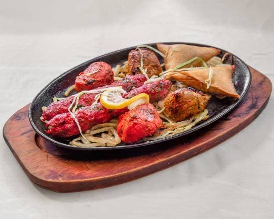 Grillades du tandoor sur plaque en fonte : poulet tikka, kebab et samossa